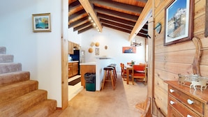 A cozy interior with wooden beams, a kitchen area, and a dining space with a view of the outdoors. - Rainbow S 4 3 Bedroom Condo by RedAwning (Mammoth Lakes)