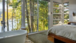 Un dormitorio con un ventanal grande, una bañera y una cama.