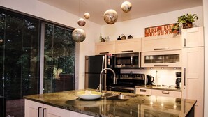 Una cocina moderna con una isla grande, electrodomésticos de acero inoxidable y vistas a través del ventanal.