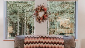 A cozy room with a large window, a grey armchair, and a chevron-patterned throw blanket.