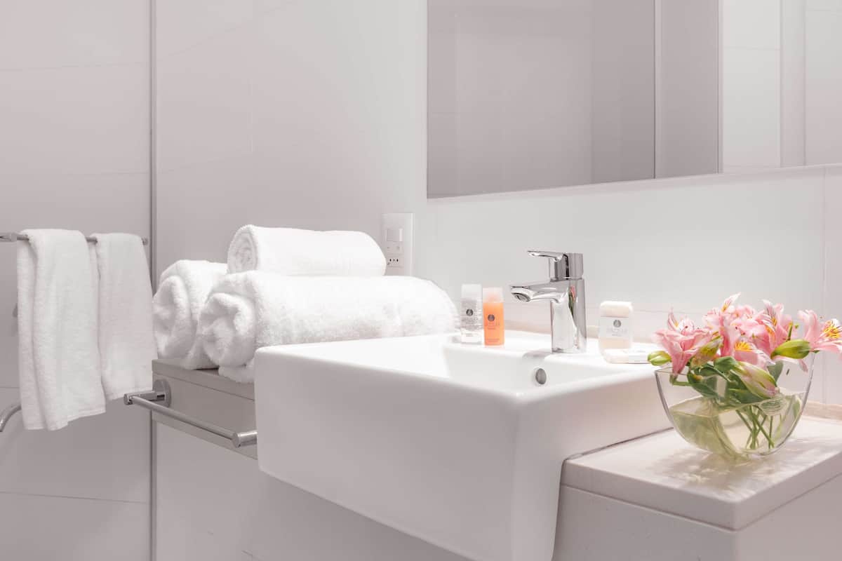 A modern bathroom with a white sink, a mirror, and a towel rack.