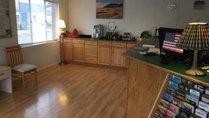 Una cocina con armarios de madera, una cafetera, una lámpara y un escritorio con una silla.