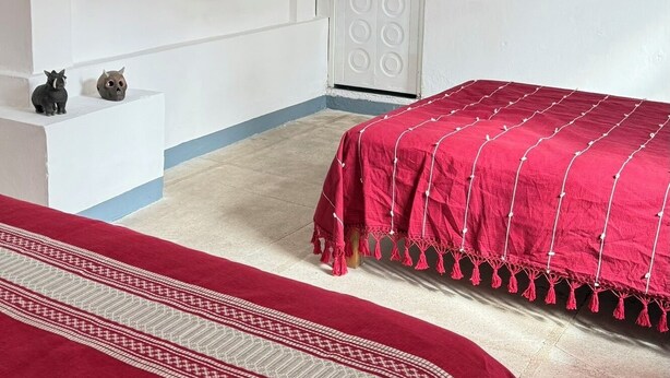 A bedroom with two beds, a TV, and a door with a circular pattern. - Casa Porfirio (Oaxaca)