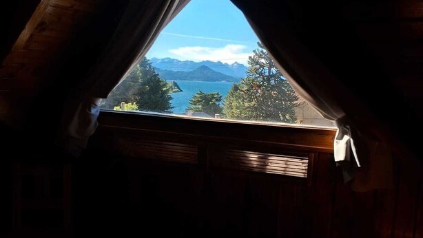A bedroom with a view of a mountainous landscape through a skylight. - La Ponderosa Apart Hotel (San Carlos de Bariloche)