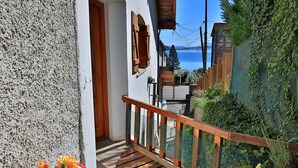 A wooden balcony with a metal railing, a white wall, and a view of the sea. - La Ponderosa Apart Hotel (San Carlos de Bariloche)