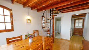A wooden dining table with chairs, a flower vase, and a spiral staircase leading to an upper level. - La Ponderosa Apart Hotel (San Carlos de Bariloche)
