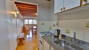 A kitchen with a gas stove, sink, and wooden benches. - La Ponderosa Apart Hotel (San Carlos de Bariloche)