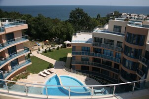 Un hotel moderno con piscina, asientos al aire libre y vistas al mar.