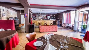 Un restaurant doté d’un bar, de nappes rouges et marron, et proposant différents types de sièges.