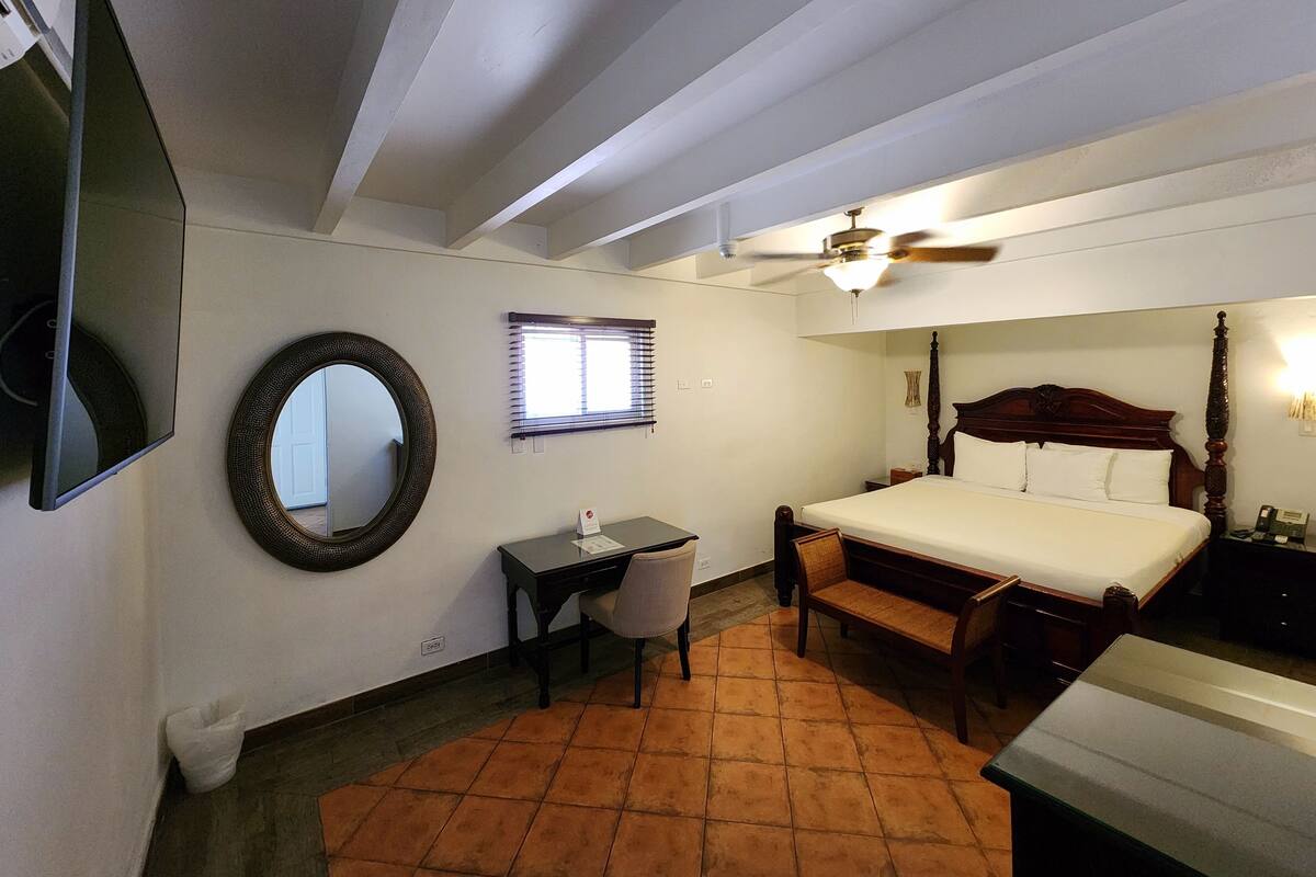 Une chambre à coucher comprenant un lit, un bureau, une chaise et un ventilateur de plafond.