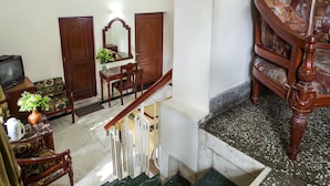 Habitación de varios niveles con escalera, muebles de madera, un televisor y un espejo decorativo.