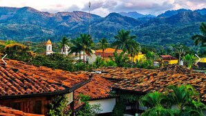 A village with terracotta-roofed houses, palm trees, and a church with a bell tower. - Marina (Copan)