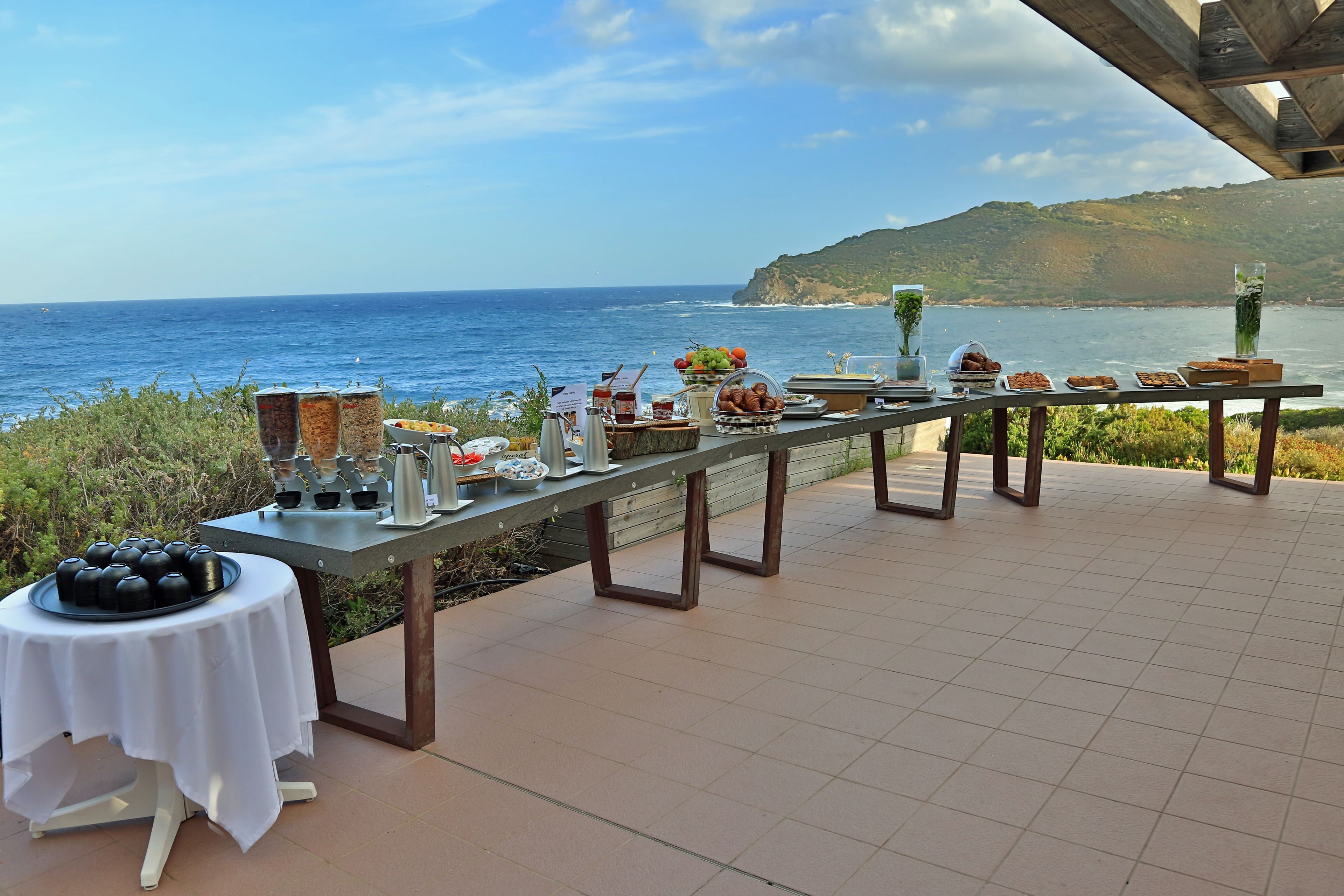 Una mesa de buffet con diferentes alimentos y vista al océano.