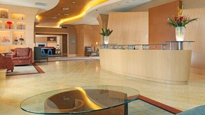 Un vestíbulo amplio con mostrador de recepción, zona de estar y una mesa de centro de cristal.
