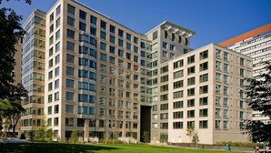 Un edificio de varios pisos con un diseño arquitectónico moderno, que combina fachadas de vidrio y concreto.