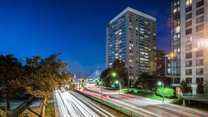 A nighttime cityscape with a tall building, a bridge, and a busy road with light trails. - Charles River Executive Suites (Boston)