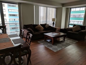 A modern living room with two sofas, a coffee table, and a dining table with chairs.