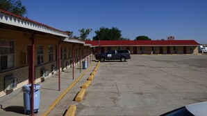 A motel with a red roof and yellow walls, featuring a parking lot and a blue dumpster. - Carrizozo Inn (Carrizozo)