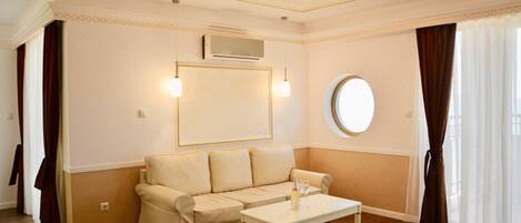 A living room with a beige sofa, a white coffee table, and a round mirror on the wall.