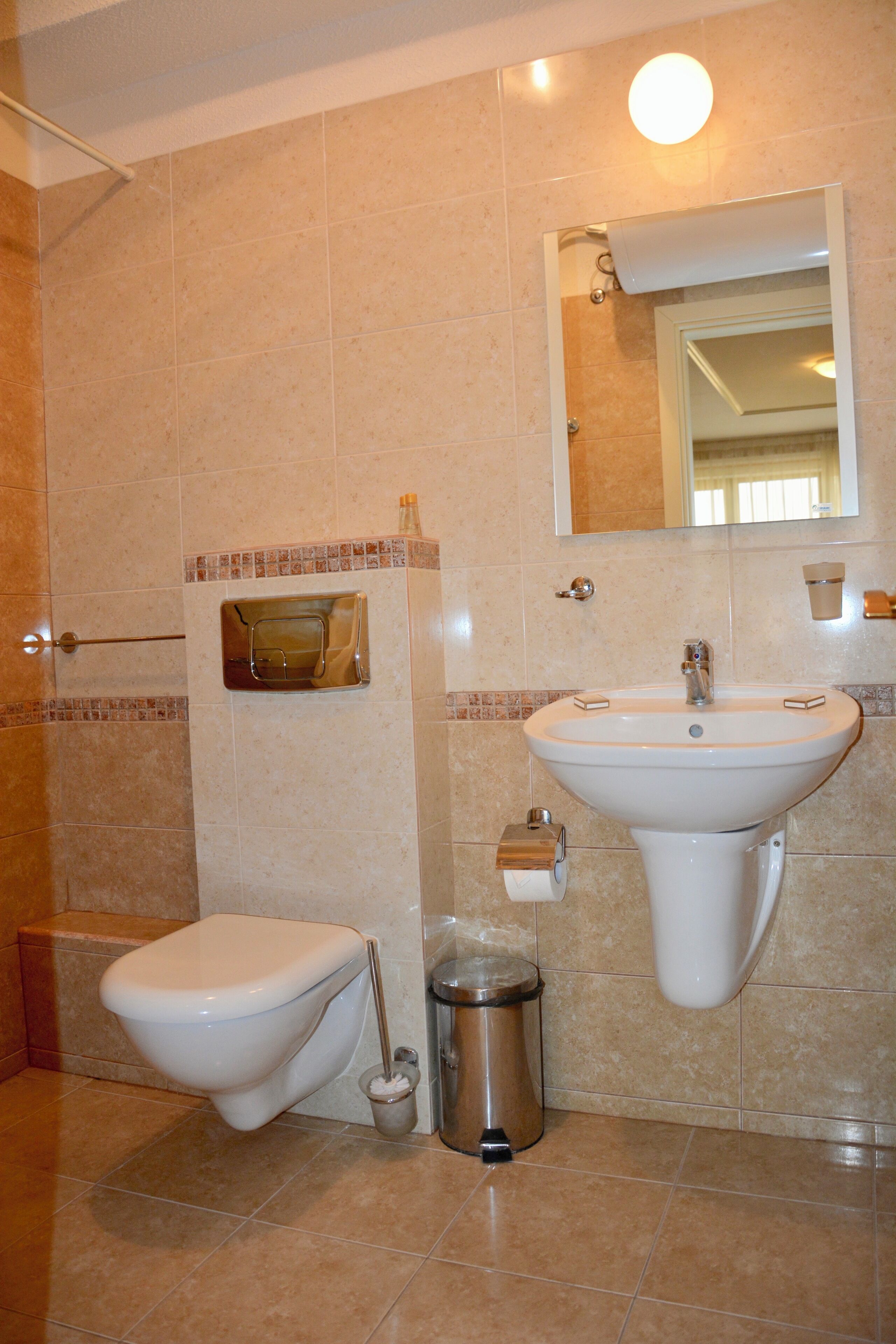 Ein Badezimmer mit Toilette, Waschbecken, Spiegel und Dusche.