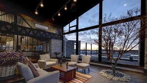 A modern interior with a large window, a stone wall, and a seating area with a coffee table. - Hotel Palacio de Sal (Uyuni)