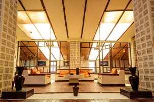 Un salón amplio con techo alto, vigas de madera y ventanas grandes.