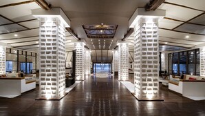 A modern hotel lobby with a central staircase, high ceilings, and a view of the outside. - Hotel Palacio de Sal (Uyuni)