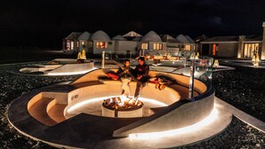 A modern resort with a central fire feature, outdoor seating, and a pool area. - Hotel Palacio de Sal (Uyuni)