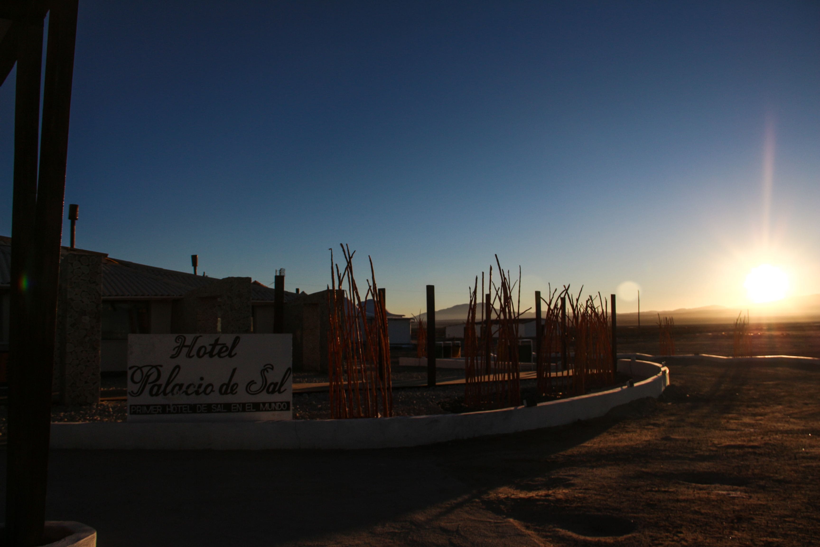 A hotel sign with the name "Hotel Palacio de Sal" and a clear view of the sunset in the background.