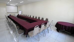 Une salle de conférence équipée d’une longue table, de chaises, d’un écran de projection et d’un tableau blanc.