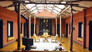 A covered outdoor area with a wooden table and chairs, a flower arrangement, and a pathway leading to a building entrance.