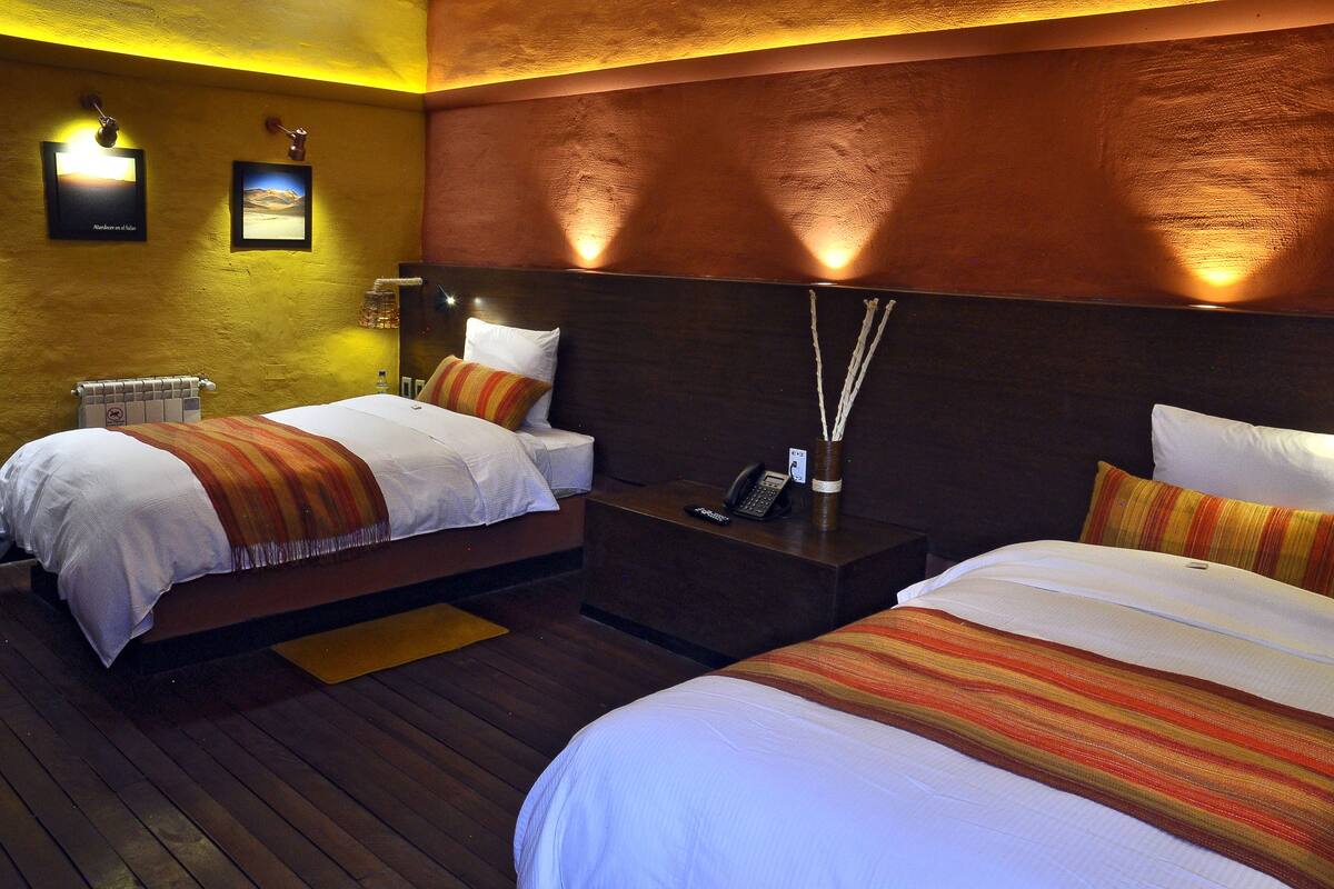 Een hotelkamer met twee bedden, een houten vloer en een telefoon aan de muur.