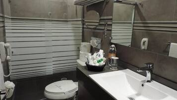 Un baño moderno con inodoro blanco, lavabo y zona de ducha.