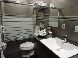 Un baño moderno con inodoro blanco, lavabo y zona de ducha.