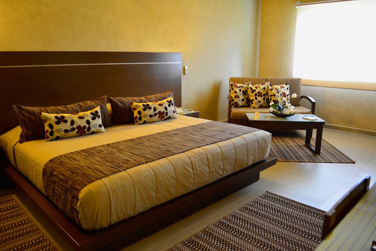 Habitación de hotel con una cama grande, un sofá y una pequeña mesa con una planta.