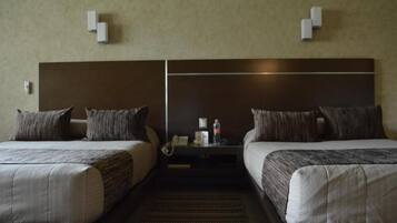 Ein Hotelzimmer mit zwei Betten, einem Nachttisch und einem an der Wand befestigten Telefon.