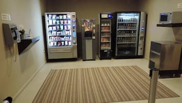 A hotel lobby with vending machines, a reception desk, and a microwave on a shelf.