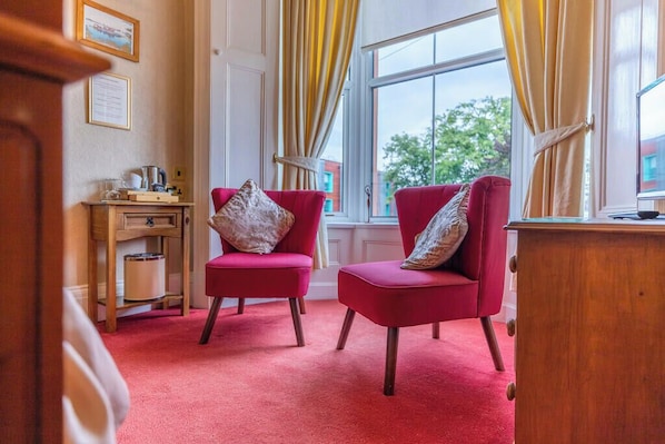 A room with two red chairs, a wooden desk, and a window with yellow curtains. - Glendale Guest House Penrith (Penrith)