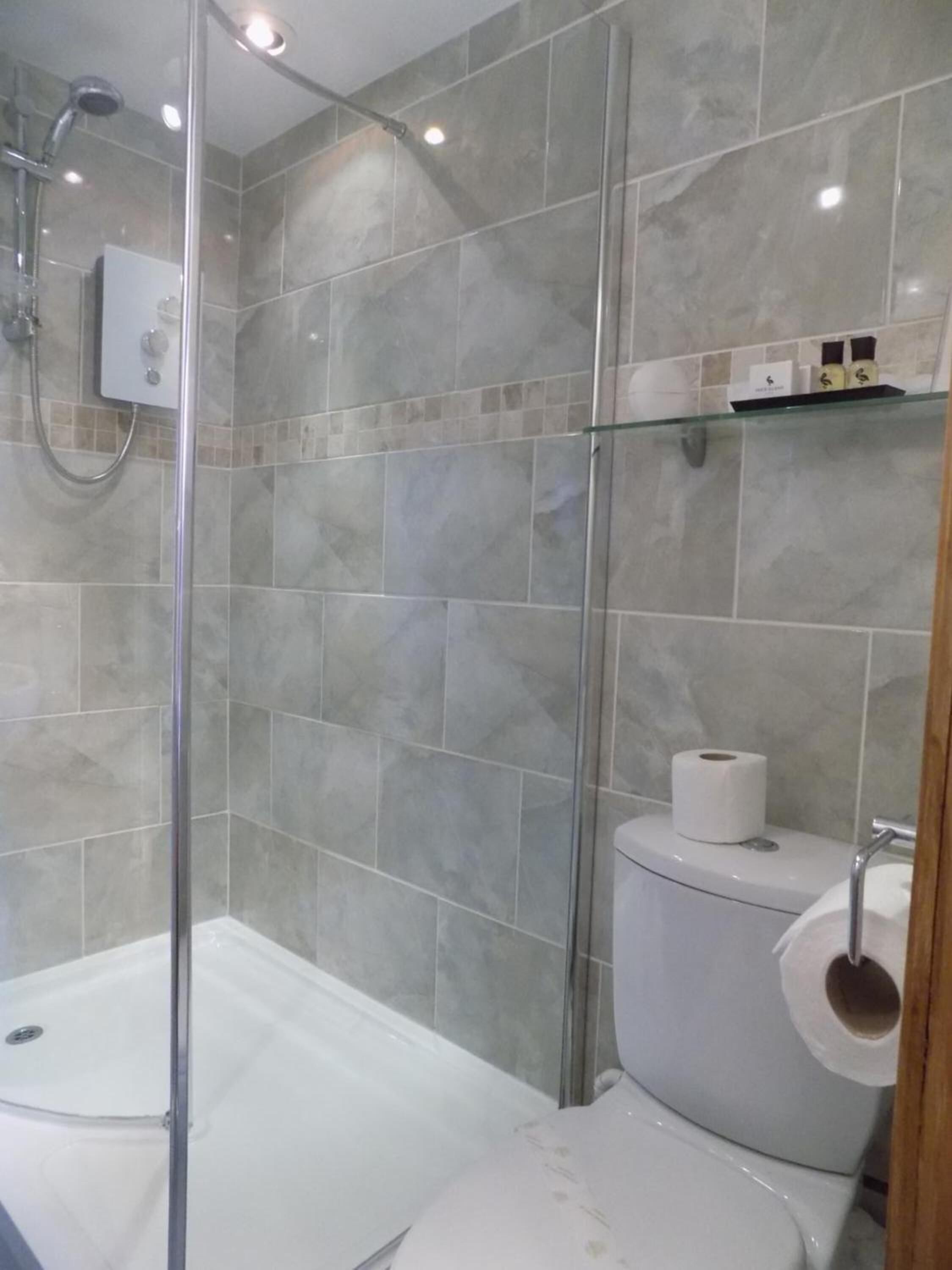 Uma casa de banho moderna com cabine de duche em vidro, sanita e lavatório.
