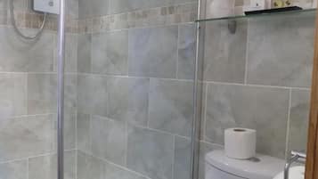 Uma casa de banho moderna com cabine de duche em vidro, sanita e lavatório.