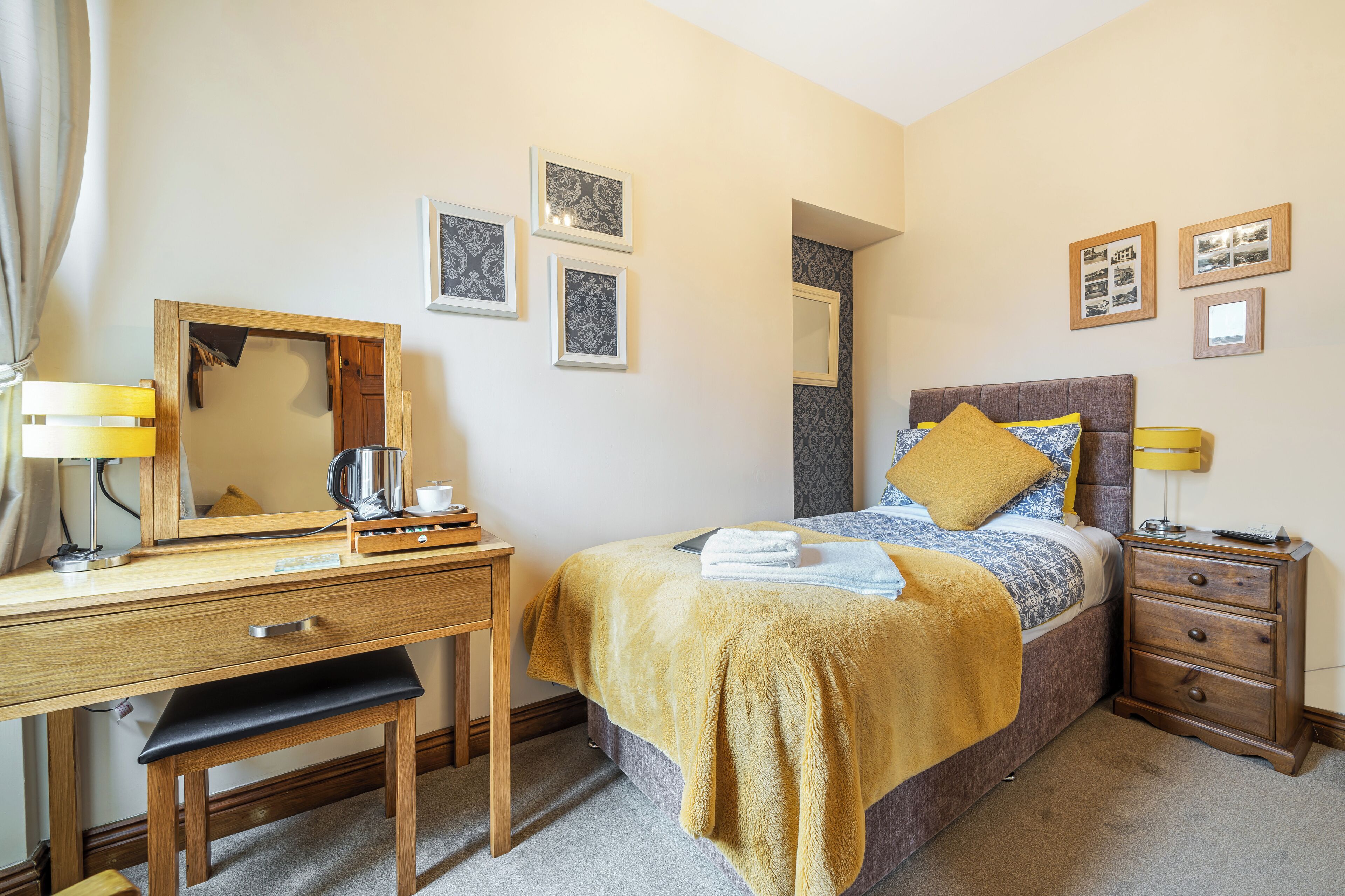 Un dormitorio con cama, mesita de noche, escritorio, silla y espejo.
