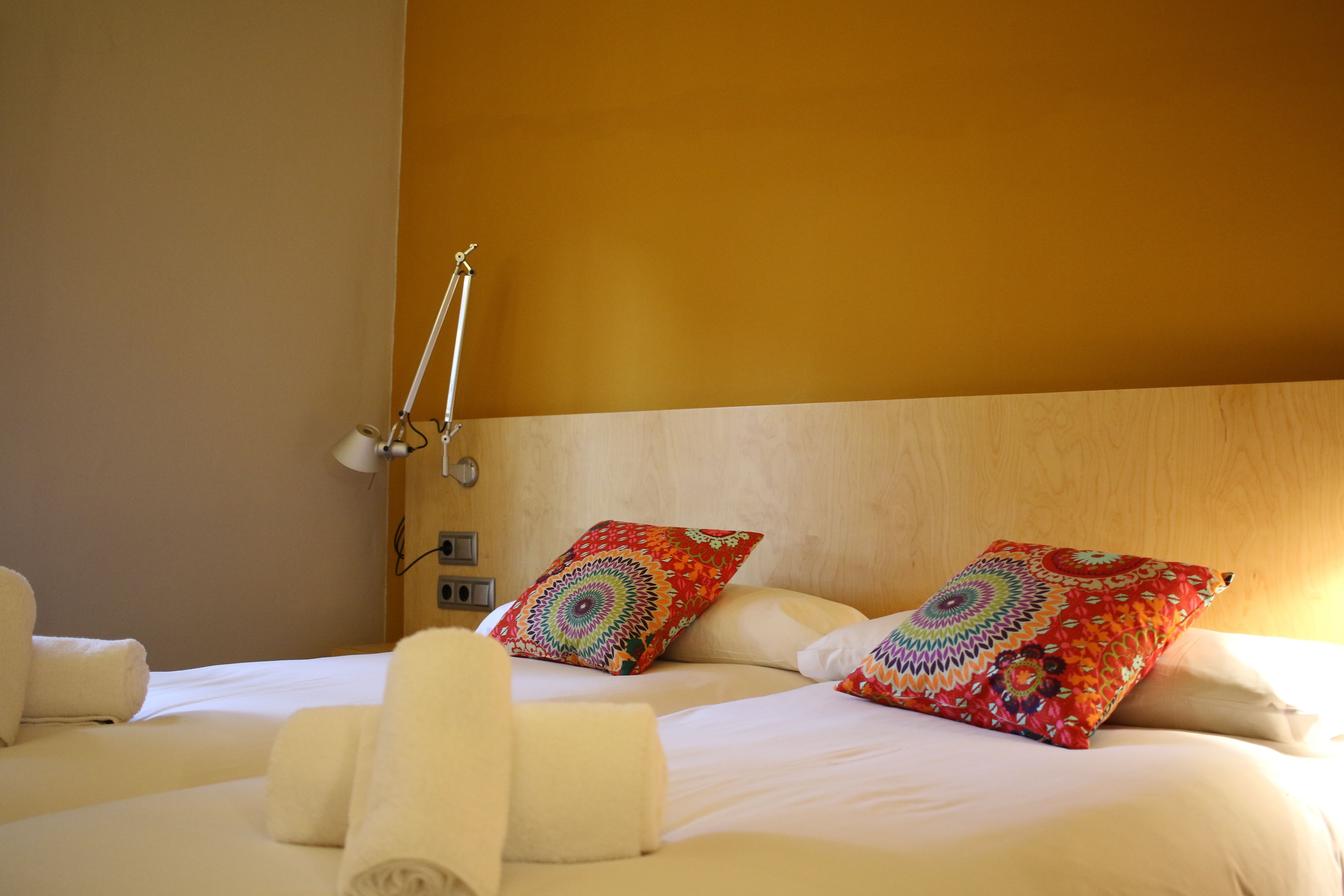 Quarto de hotel com cama, duas almofadas, abajur e toalhas.