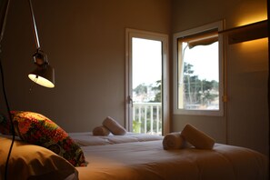 A hotel room with a bed, a lamp, and two windows.