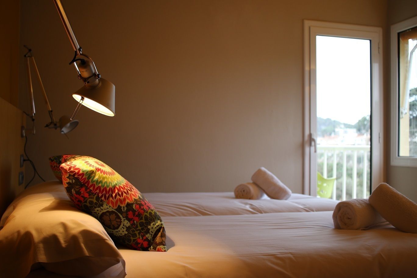 A bedroom with a bed, pillows, a lamp, and a view of a balcony.