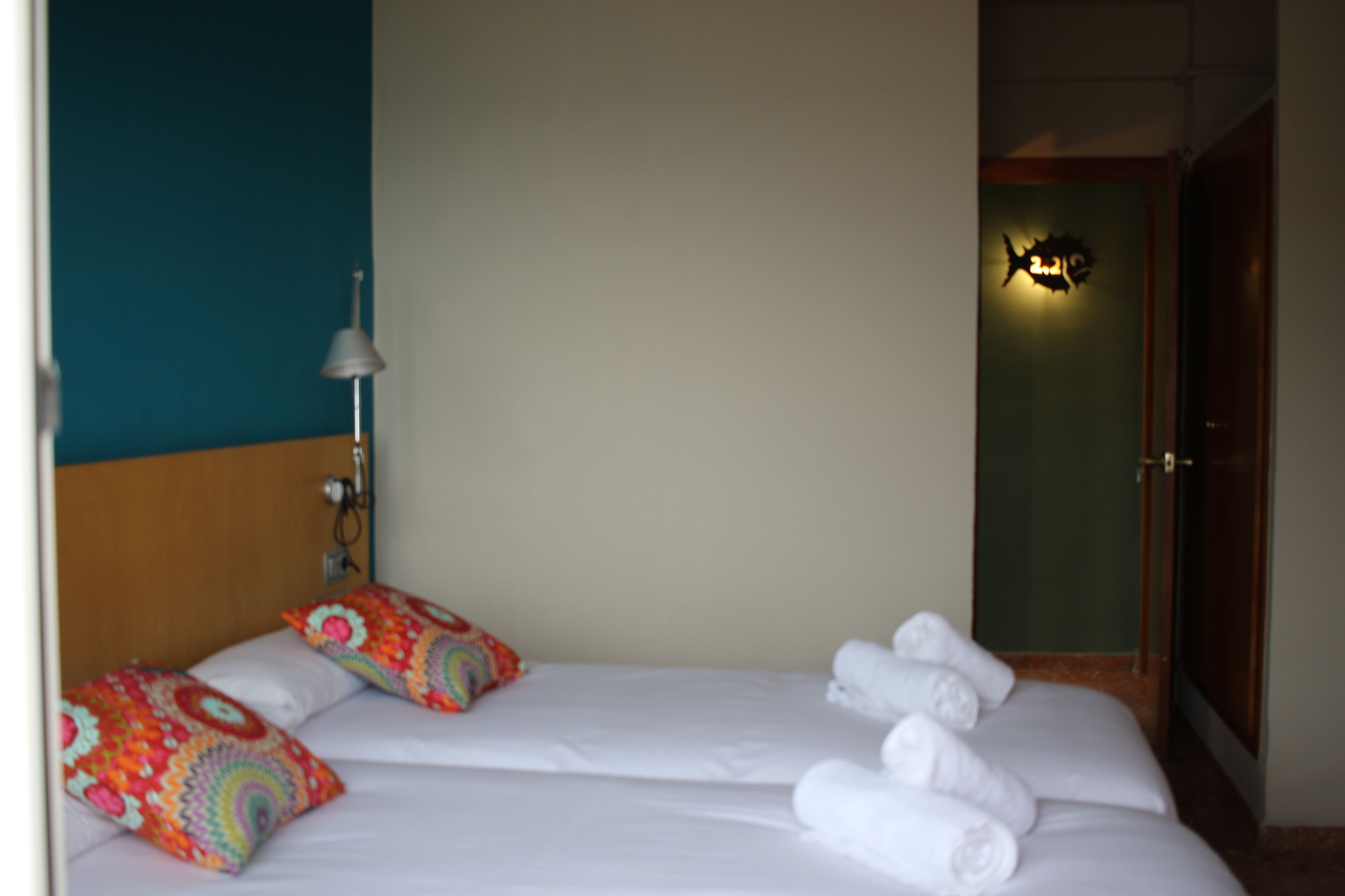 Ein Hotelzimmer mit Bett, Kissen, einer Lampe und einer Tür.