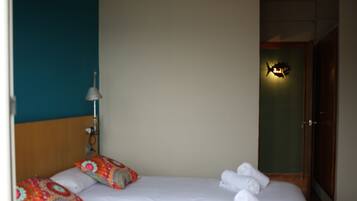 Ein Hotelzimmer mit Bett, Kissen, einer Lampe und einer Tür.