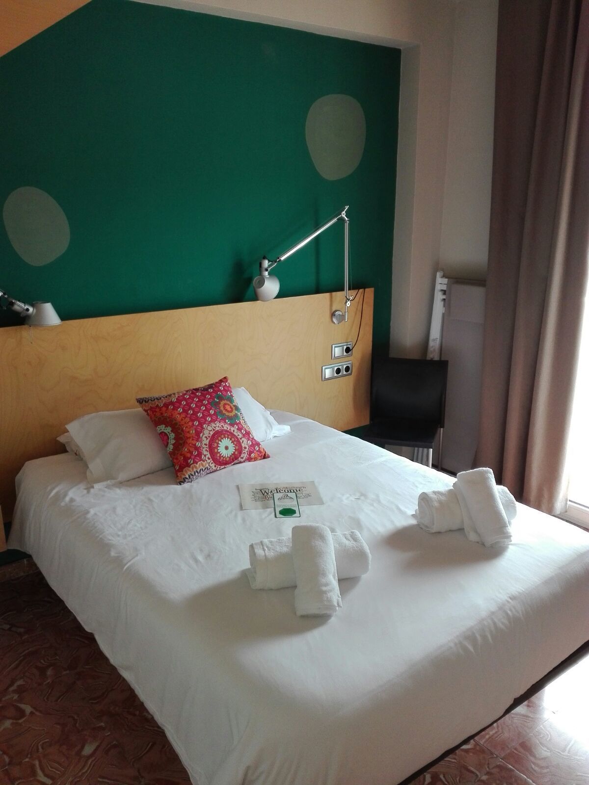 Una habitación de hotel con una cama bien hecha, una tarjeta de bienvenida y toallas.