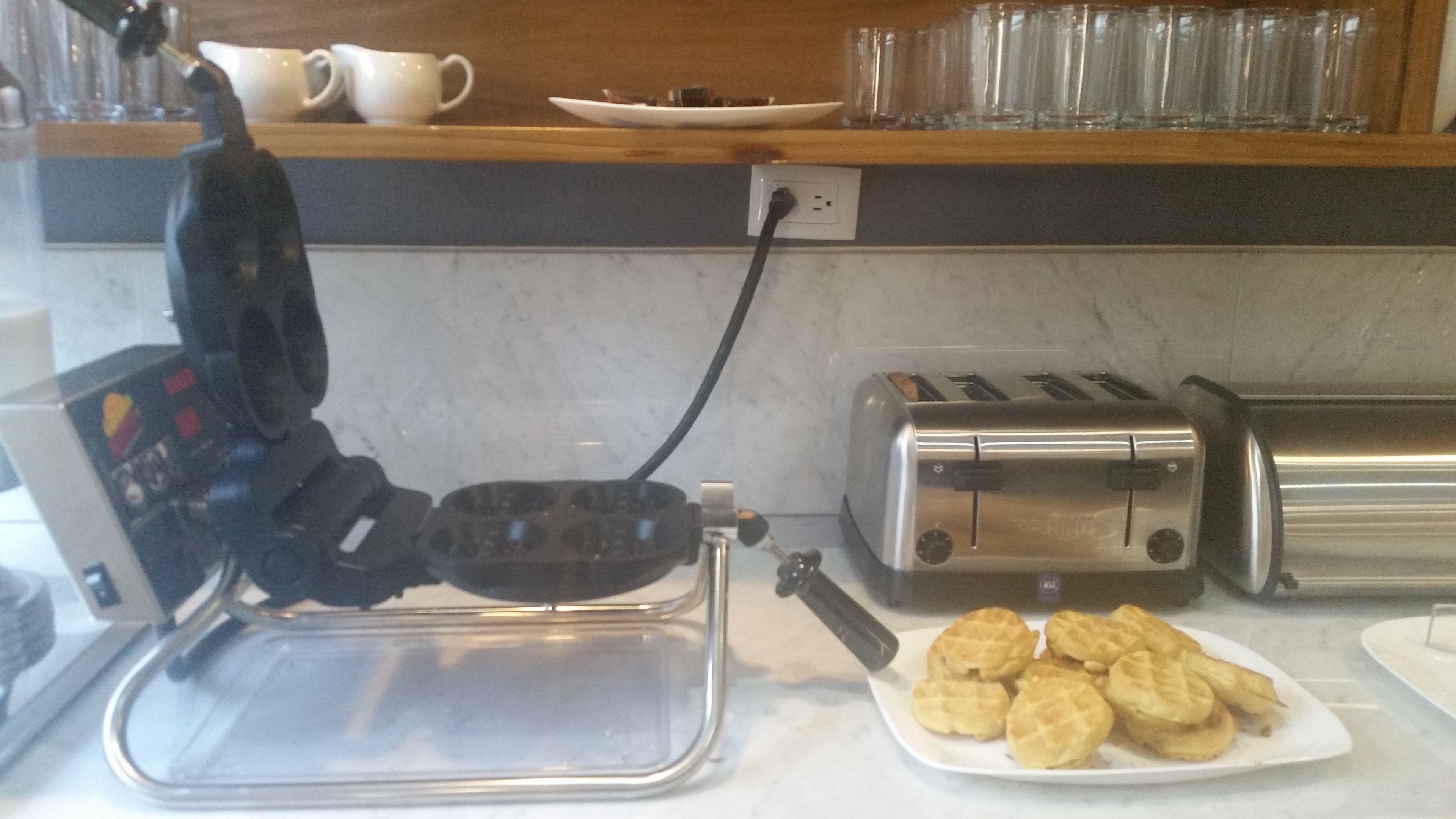 Una cocina con un fabricante de gofres, dos tostadoras y un plato de gofres.