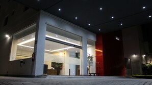 Un edificio moderno con recepción, ventanas amplias y una pared decorativa roja.