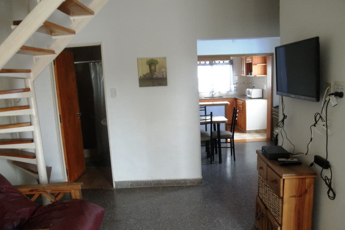 Un espacio habitable compacto con una escalera, un comedor y una cocina.